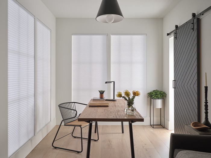 Large office with four windows and light colored shades.